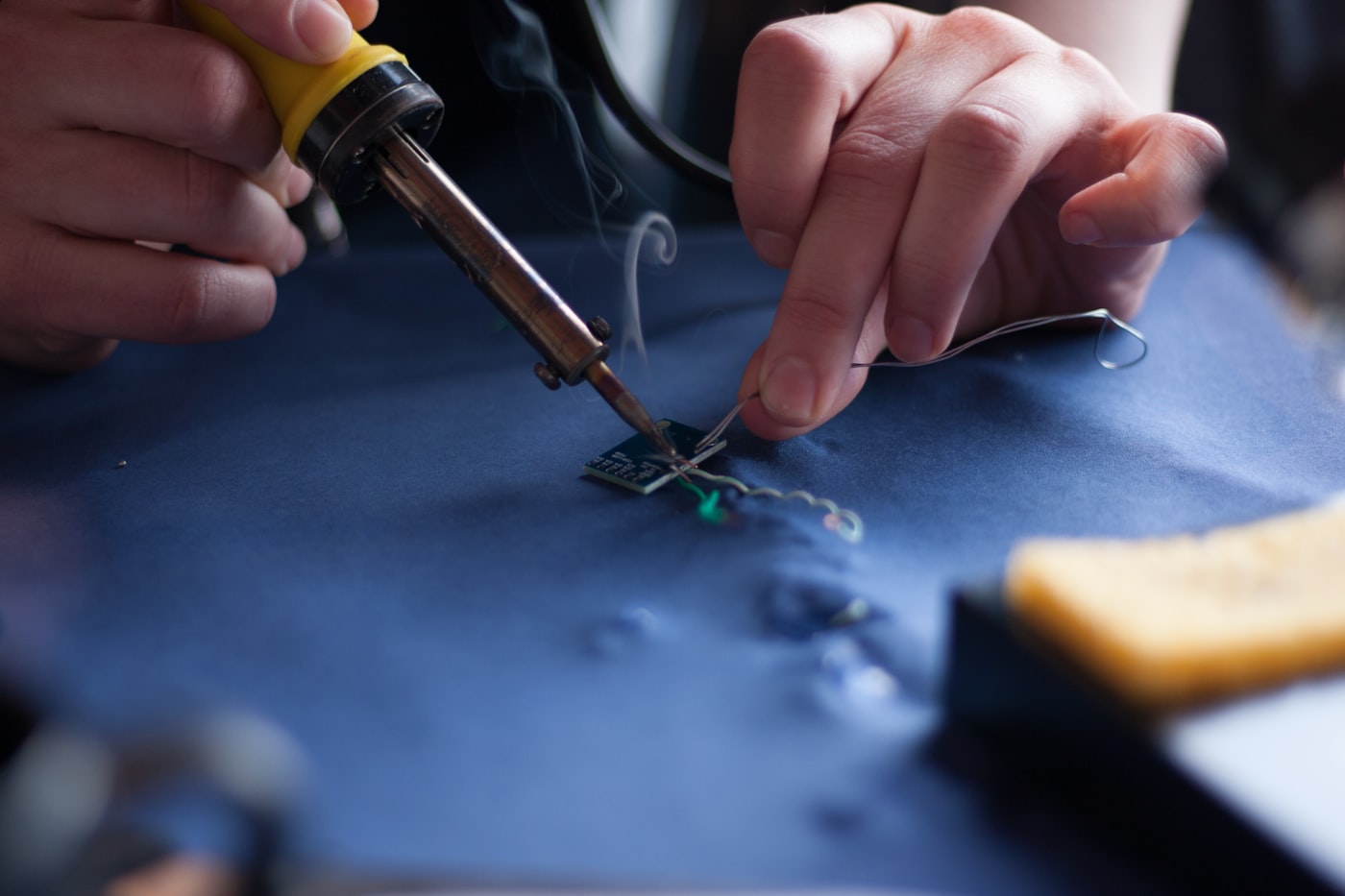 Technician's hands soldering a circuit board close up